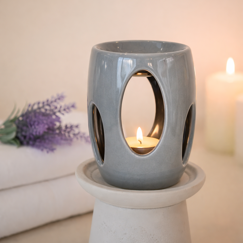 Gray ceramic wax melt burner with a candle on a white surface, with a blurred background