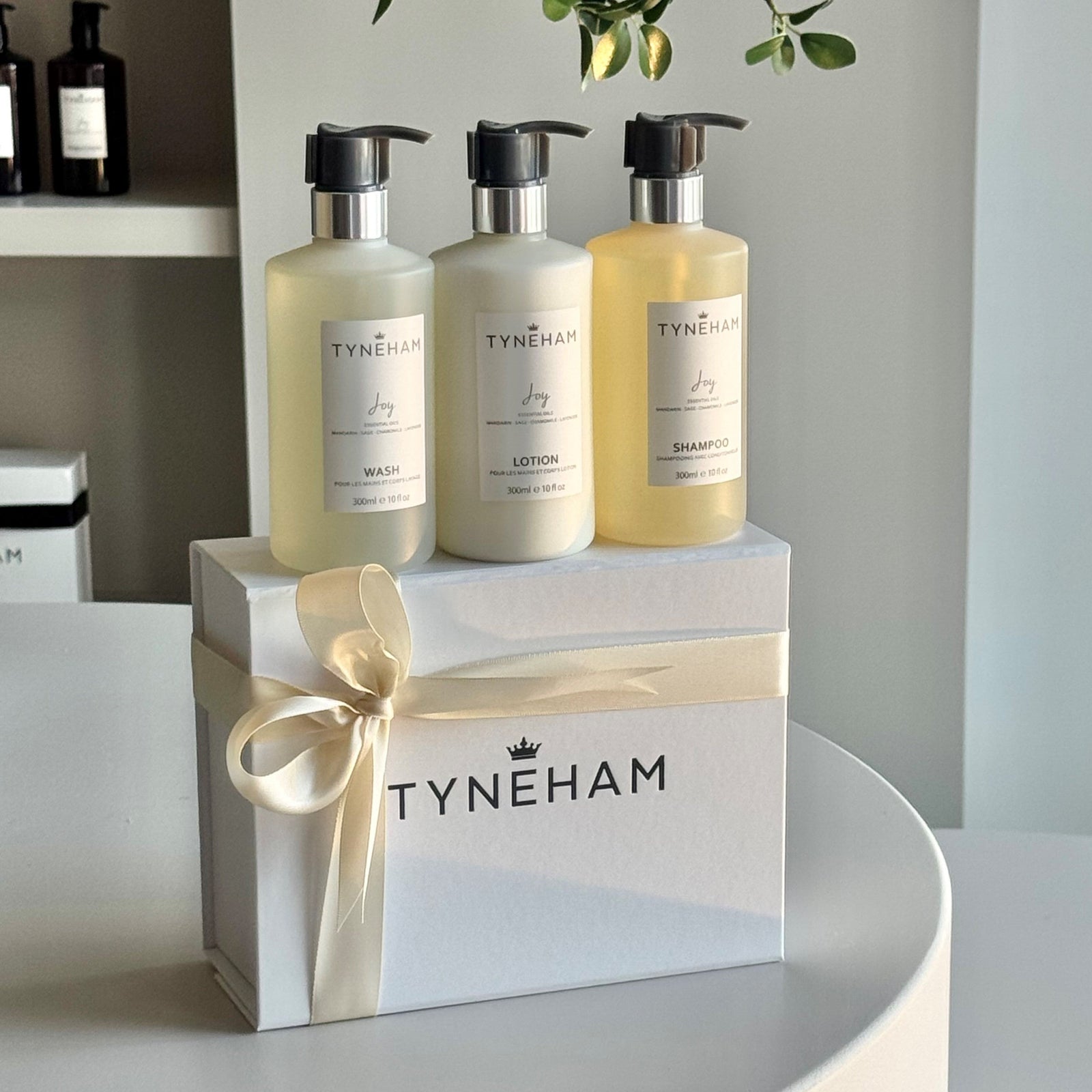 Three bottles of Tyneham products on a white box with a ribbon, against a neutral background.